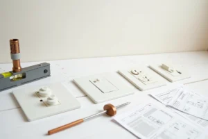 Comparatif des gammes d'interrupteurs Legrand Celiane, Mosaic et Neptune disposés sur un plan de travail de bricolage